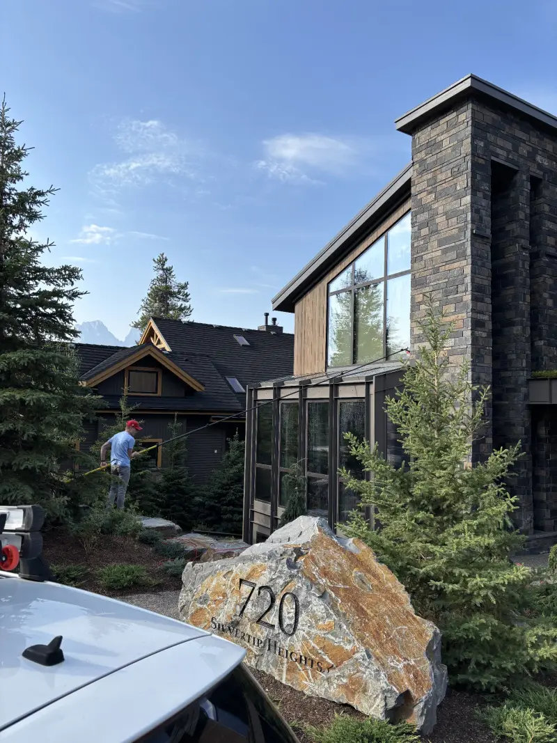 Technician performing exterior cleaning on a luxury mountain home